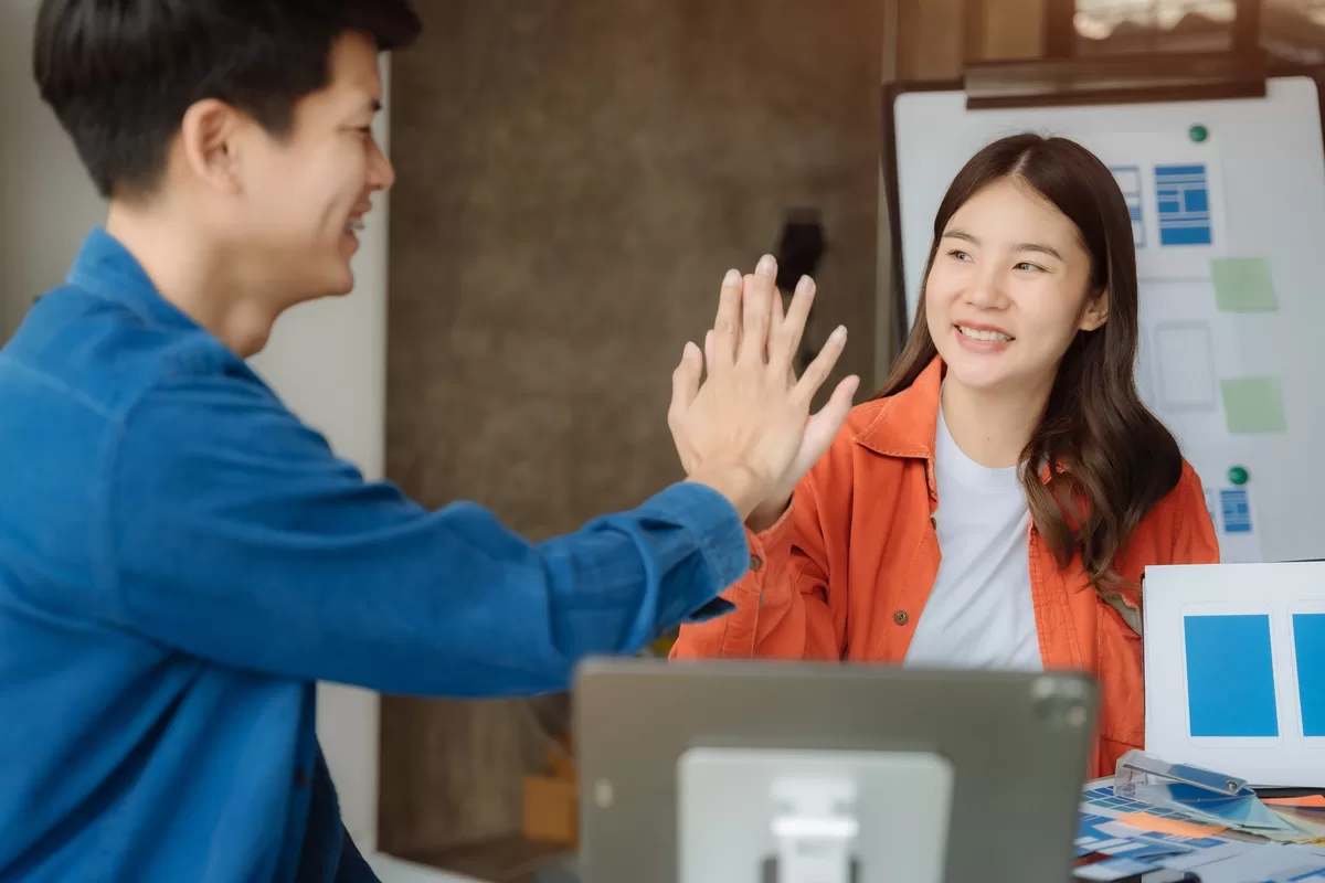 Two colleagues high-fiving in a business meeting.