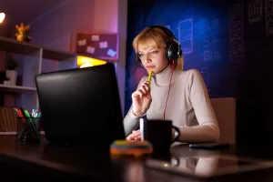 Focused woman working late at computer with headphones.