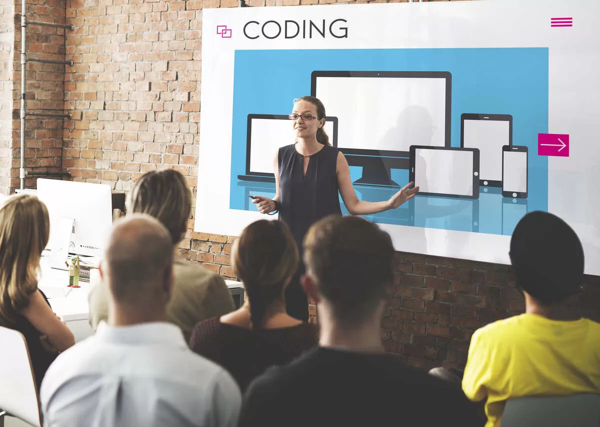 Coding seminar with presenter and audience in brick-walled room.