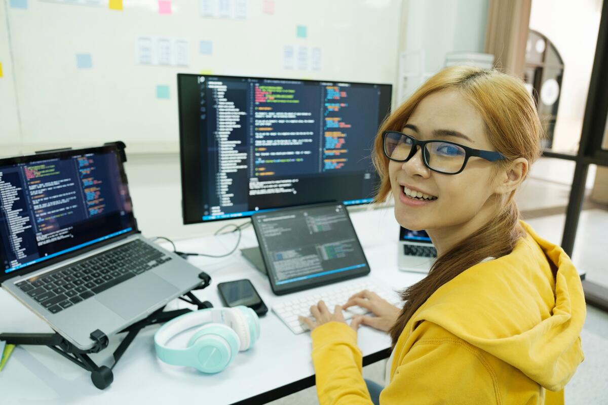 Female web designer working with multiple screens and laptop.