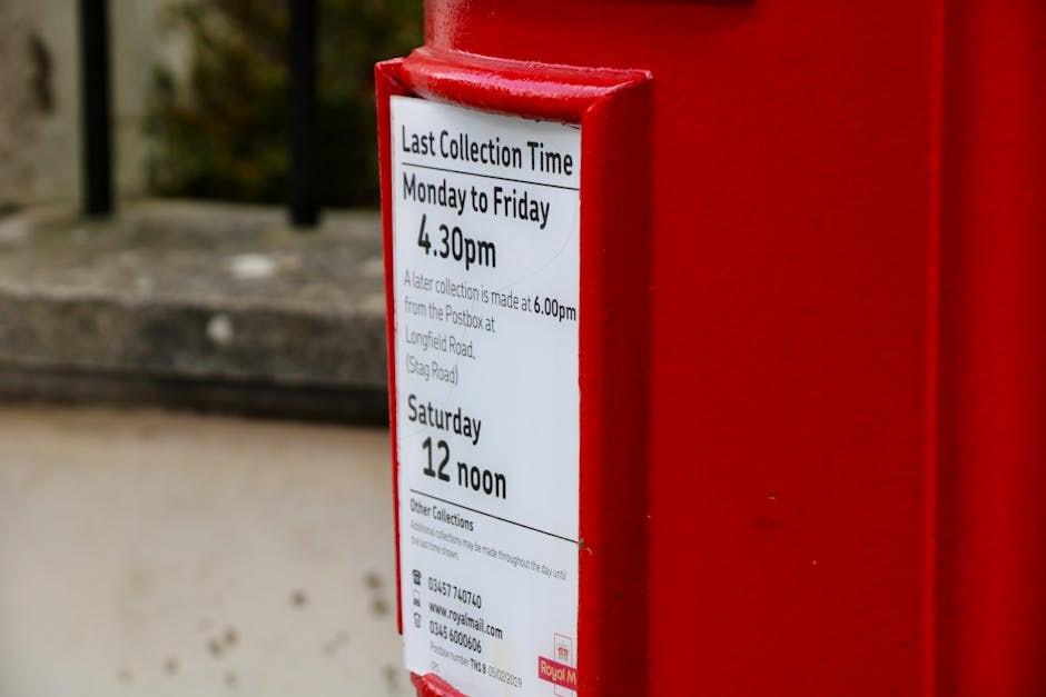Close-up of a red Royal Mail postbox with collection times in Tunbridge Wells, UK.